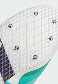 Suola di scarpa con tacchetti in bianco con superficie testurizzata, caratterizzata da accenti blu, chiodi in metallo e un motivo a griglia per la trazione.