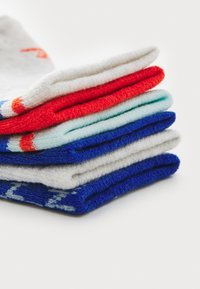 Stapel von fünf Socken in verschiedenen Farben: rot, hellblau, weiß und blau, mit einem strukturierten Strickmuster. Jede Socke hat kontrastierende Farbakzente.