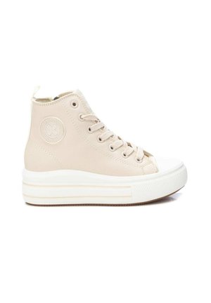 Zapatilla beige de caña alta con suela gruesa de goma blanca, puntera redonda, cordones y un parche circular con el logo en el lateral del tobillo.
