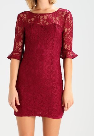 Robe en dentelle bordeaux avec des manches transparentes trois quarts et une coupe ajustée. Dotée d'un décolleté bateau et d'un motif floral en dentelle sur l'ensemble.