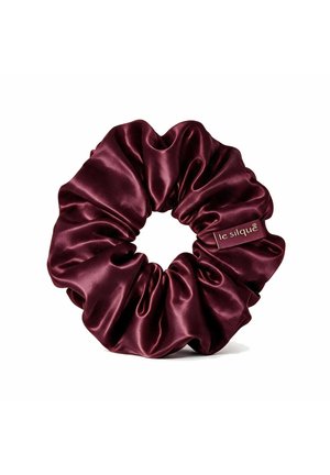 Dunkelburgunderfarbener Satin-Scrunchie mit gerafftem Stoff und einem kleinen Stoffetikett mit der Aufschrift "le silque" auf weißem Hintergrund.