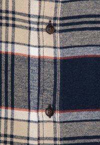 Koszula w kratę w odcieniach beżu, granatu i pomarańczu; wykonana z tkaniny o splocie; posiada ciemne guziki i teksturowane wykończenie.