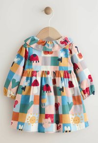 Robe en coton colorée avec un motif carré comportant des fleurs, des coccinelles et un chat. Elle possède un col à volants et des manches longues.