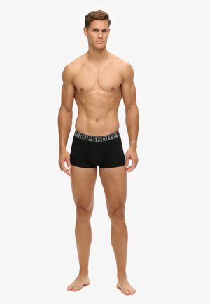 Boxer-briefs noirs avec une taille extensible arborant un logo "SUPERDRY" gris. Tissu lisse, design ajusté et longueur mi-cuisse.