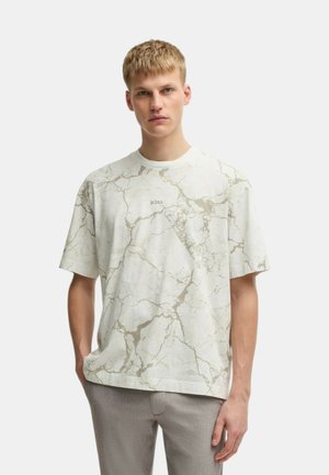 T-shirt a maniche corte con motivo marmorizzato in crema chiaro e dettagli beige, dotato di scollo rotondo e vestibilità rilassata. Dettaglio del logo sul davanti.