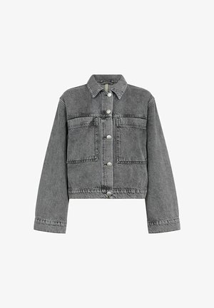 Siva traper jakna s krojenjem iznad struka, srebrnim dugmadi na pritisak, dva džepa na prsima i klasičnim ovratnikom. Neuredan rub i vidljivi detalji šivanja.