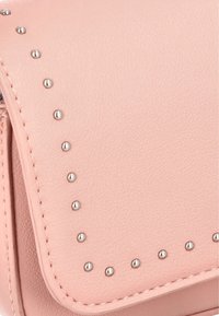 Rosa imitationsläder handväska med nitar längs kanten, med en texturerad yta och en klaffstängning.