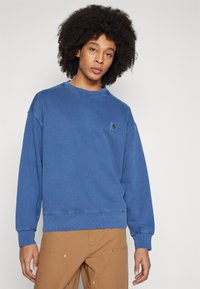 Sudadera azul de algodón, con cuello redondo, puños acanalados y un pequeño parche del logo en el pecho, con un corte relajado.