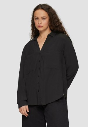 Black button-up shirt made of smooth fabric, featuring a V-neckline, two front pockets, and long sleeves with button cuffs.