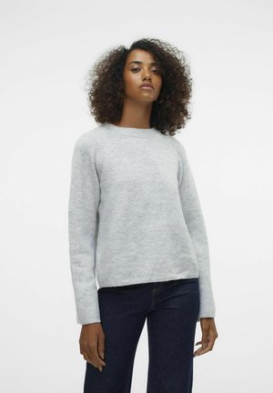 Ljusgrå tröja i ett mjukt, texturerat tyg. Har rund hals, långa raglanärmar och en något kortad fåll. Stylen matchas med mörka jeans.