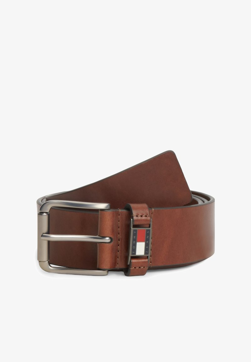 Ceinture en cuir marron avec boucle métallique argentée, roulée, avec une petite étiquette rectangulaire Tommy Jeans près de la boucle.