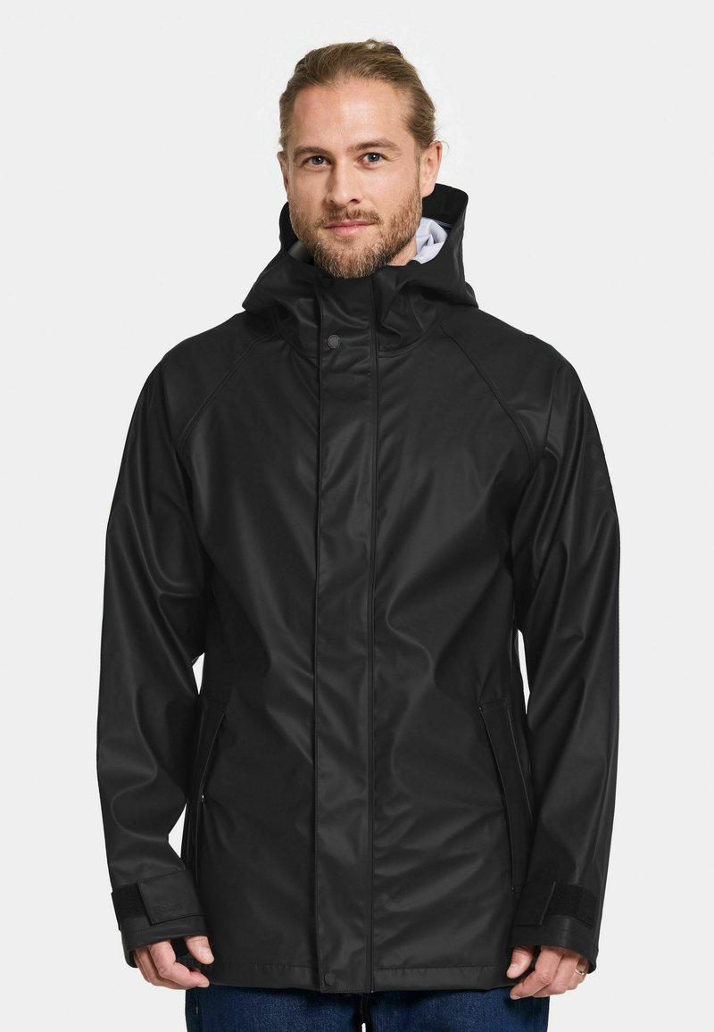 Svart vattentät jacka med huva, som har en frontdragkedja, tryckknappar och kardborremuddar. Slät textur och stilren design.