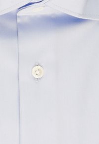Tessuto azzurro chiaro con una texture liscia, caratterizzato da un singolo bottone bianco al colletto, cucito con filo abbinato.