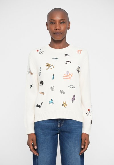 Creme striktrøje med farverig brodering af insekter og blomster. Ribkanter ved ærmer og bund. Kombineret med blå lige jeans.