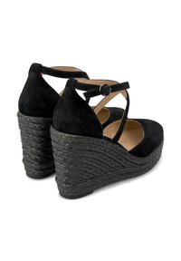 Zwarte suedine wedge schoenen hebben een geweven platformhiel, een verstelbare enkelband en een open achterkant voor ademend vermogen.