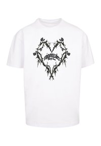 Hvit T-skjorte med et svart hjerte design av torner og blader, med teksten "migonztales" og "Family Blessed" i stilisert skript i sentrum.