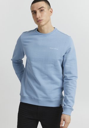 Lyseblå sweatshirt lavet af bomuld, med rund hals, ribbede manchetter og kant, med "CASUAL" trykt i hvidt på forsiden.