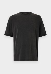 Svart kortärmad t-shirt med rund halsringning, avslappnad passform och uppvikta ärmslut. Gjord av mjukt bomullstyg med en lätt struktur.