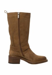 Botte Montante en Daim Marron, avec fermeture éclair sur le côté, talon empilé et accent de sangle autour de la cheville. Texture lisse avec un design classique.