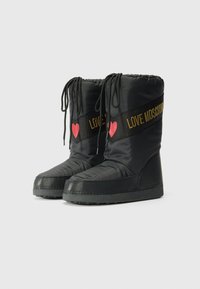 Fekete nejlon csizma lekerekített orral és texturált talppal. Piros szív részletekkel és kontrasztos "LOVE MOSCHINO" aranyszínű szalaggal rendelkezik.