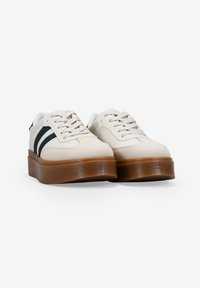 Zapatillas de plataforma blancas con rayas verde oscuro. Superior de tela suave, puntera redonda y suela de goma. Diseño con cordones y seis ojales.