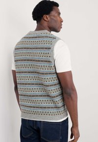 Gebreide mouwloze trui in lichtgrijs met een multicolore geometrisch patroon in blauw, bruin en crème; ronde hals, textuurstof.