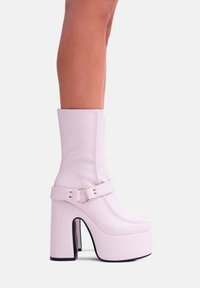 Stivali alti fucsia con finitura in finta pelle liscia, cinturino alla caviglia e design con tacco spesso. Vista di profilo laterale.