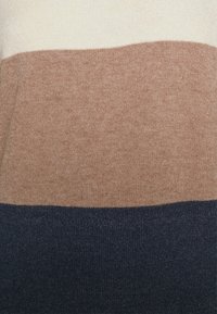 Maglione lavorato a maglia con tre strisce orizzontali: crema, marrone chiaro e blu scuro. Texture morbida con una finitura liscia e linee pulite.