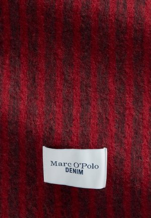 Rot gestreifter Stoff mit dunklen Streifen und einem weißen, rechteckigen Marc O'Polo Denim Markenetikett, das nahe der unteren Mitte angenäht ist.