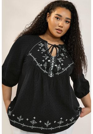 Black top made of crinkled fabric with white floral embroidery. Features a drawstring neckline and short puffed sleeves.