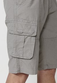 Shorts cargo gris en tissu léger avec de multiples poches, une coupe décontractée et des coutures structurées pour plus de durabilité.