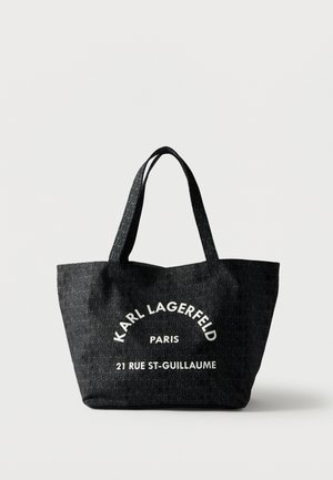 Černá taška typu tote s opakujícím se vzorem textu "KARL LAGERFELD" a bílým nápisem "KARL LAGERFELD PARIS 21 RUE ST-GUILLAUME" na přední straně.