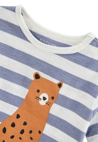 T-shirt à manches courtes rayé bleu et blanc avec un motif animalier orange, présentant des taches noires, un nez et des moustaches sur un tissu texturé.