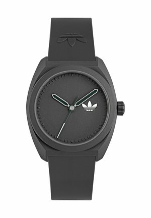 Montre noire avec un fini mat, cadran rond, aiguilles des heures et des minutes vertes, aiguille des secondes argentée, et un petit logo blanc sur le cadran.