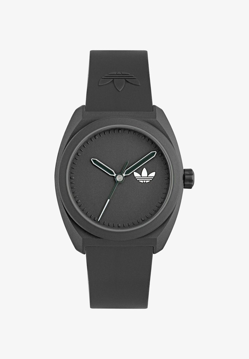 Must matte viigiga must kell, ümmargune kellanägu, rohelised tundide ja minutite näpujuhid, hõbedane sekundinäitaja ja väike valge logo kellanäol.