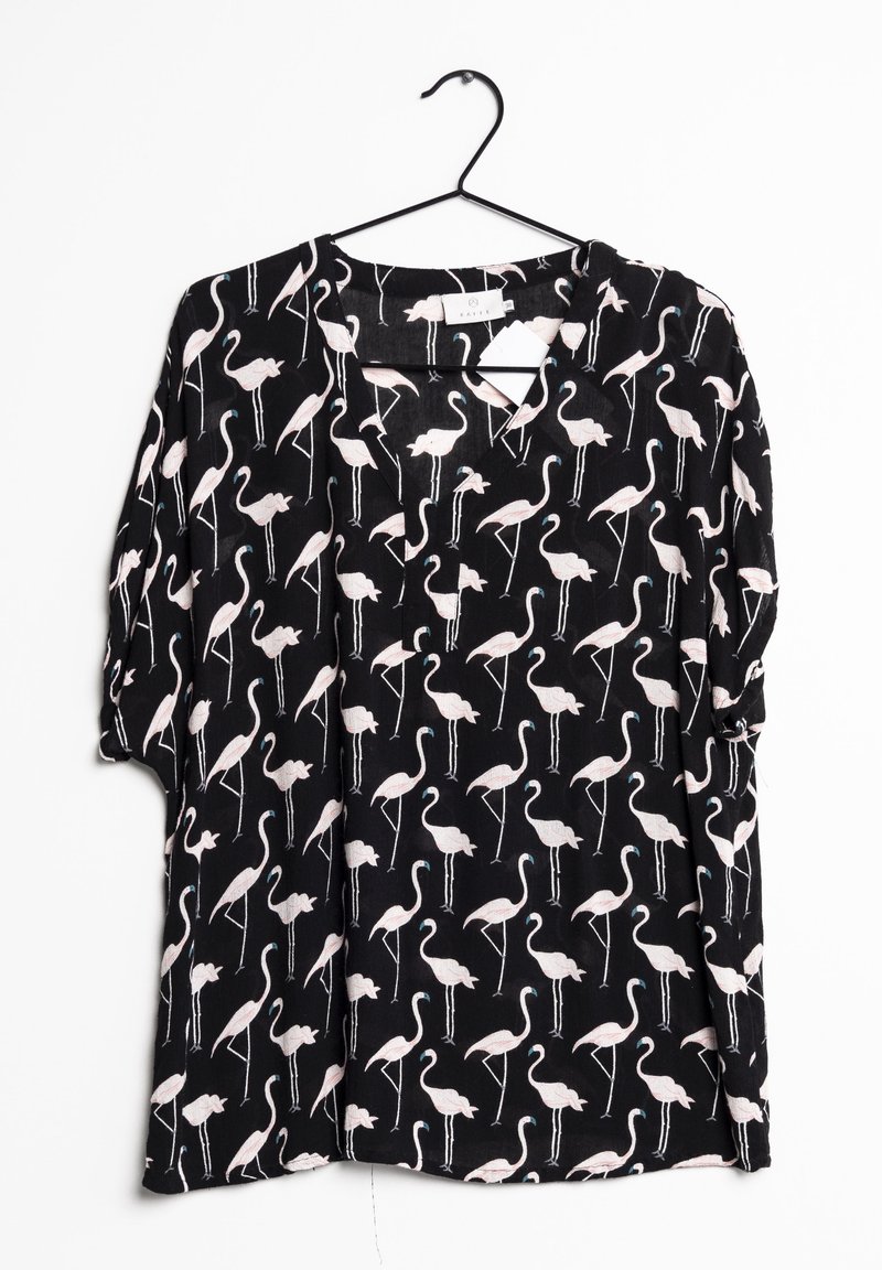 Blouse noire avec motif flamant rose clair suspendue à un cintre noir sur fond blanc.