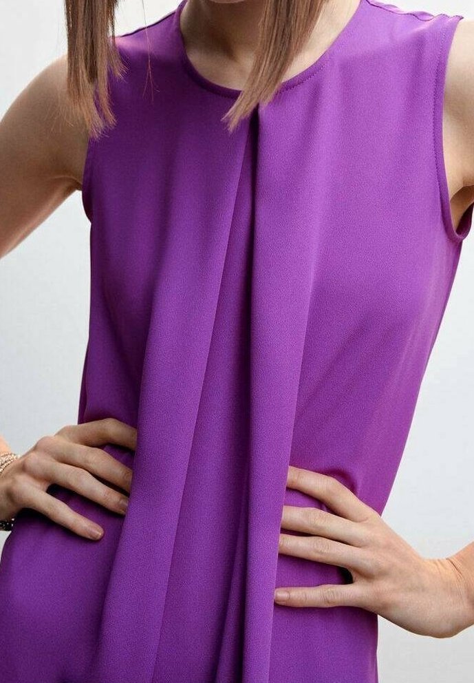 Blouse sans manches violette avec un devant plissé, en tissu léger qui tombe souplement. Texture lisse et lignes épurées.