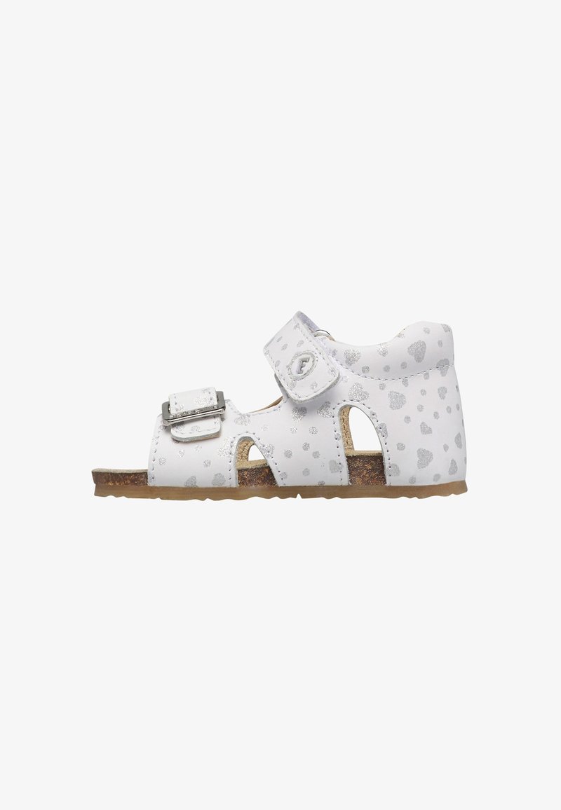 Sandale pour tout-petit blanche avec motif de cœur argenté, boucle ajustable et sangles à velcro, semelle en liège, et côtés ouverts pour la respirabilité.