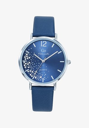 Montre à quartz avec un cadran bleu, des accents argentés et un bracelet en cuir bleu texturé. Présente des embellissements en cristal et des index horaires audacieux.