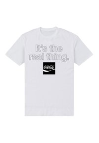 Bílá bavlněná tričko s krátkým rukávem, na kterém je šedý nápis "Je to ta pravá věc" a černé logo Coca-Coly umístěné pod nápisem.