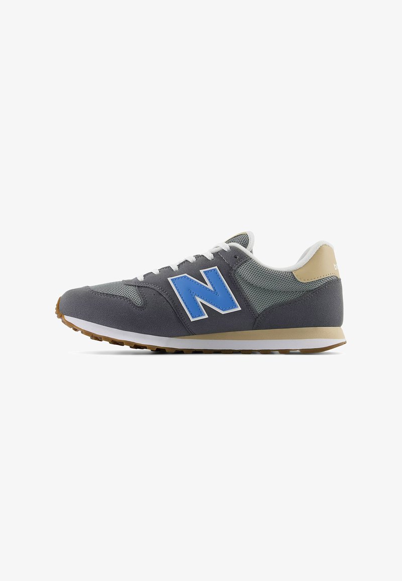 Baskets de sport grises avec une tige en mesh, logo "N" bleu, lacets blancs et accents beige clair sur le talon, dotées d'une semelle en caoutchouc.