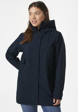 Chaqueta impermeable de color azul marino con cuello alto, capucha ajustable y dos bolsillos laterales. Textura suave y diseño liso, adecuada para usar al aire libre.