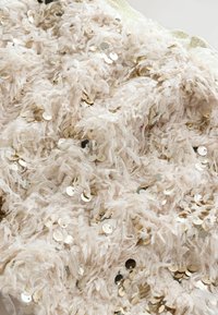 Struktureret stof i lys beige, med fluffy fibre og spredte metallic guld pailetter, samt en skinnende kantdetalje.