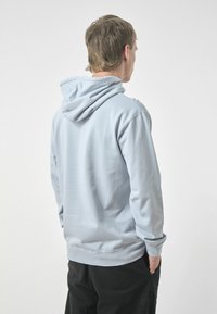 Light blue hoodie in cotton blend, featuring a spacious hood and ribbed cuffs. Smooth texture, casual fit, with a plain back design.