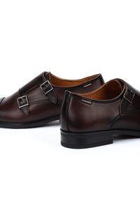 Bruine leren schoenen met dubbele gespen, een ronde neus en een gladde afwerking, met een zwarte rubberen zool en een tan kleurige binnenvoering.
