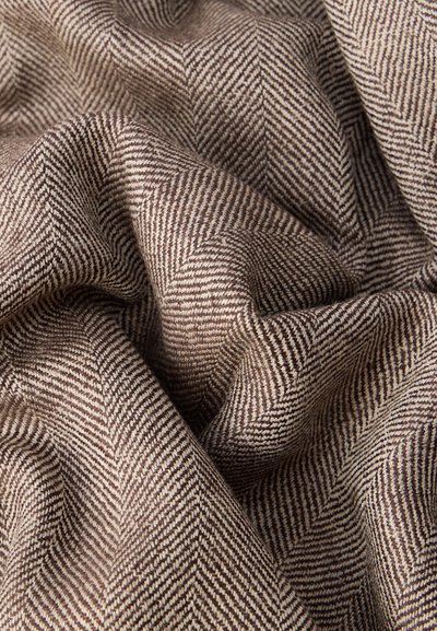 Salmikarja mustriga kangas tekstuurse pinnaga, kus vahelduvad pruunid ja kreami triibud, moodustades diagonaalse mustri.