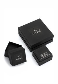 Sorte gaveæsker i papir i tre størrelser med logoet "Kuzzoi." Den største æske er rektangulær, mens de andre er kvadratiske.