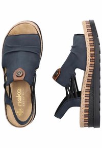 Granatowe sandały z miękką cholewką, elastycznymi akcentami, okrągłym brązowym guzikiem, środkową częścią obuwia owiniętą jutą oraz teksturowaną czarną gumową podeszwą.