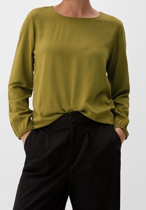 Olijfgroene blouse met lange mouwen, een ronde halslijn, geplooide manchetten en lichtgewicht stof, gecombineerd met zwarte, relaxed fit broek.