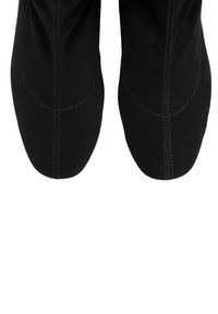 Zapatos de tela negra con un acabado suave, punta redondeada y costuras contrastantes. Material blando con un diseño flexible para mayor comodidad.